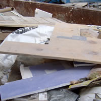 Close up image of haphazardly strewn ceilint tiles, dry-wall, and other composite building materials